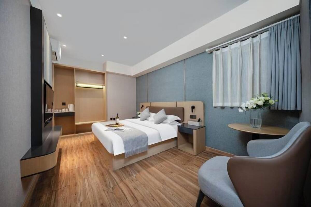 Une chambre d’hôtel moderne équipée d’un lit, de tables de chevet, d’une télévision et d’un coin salon.