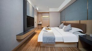 Ein modernes Hotelzimmer mit einem großen Bett, einem flachbildfernseher an der Wand und einem Nachttisch.