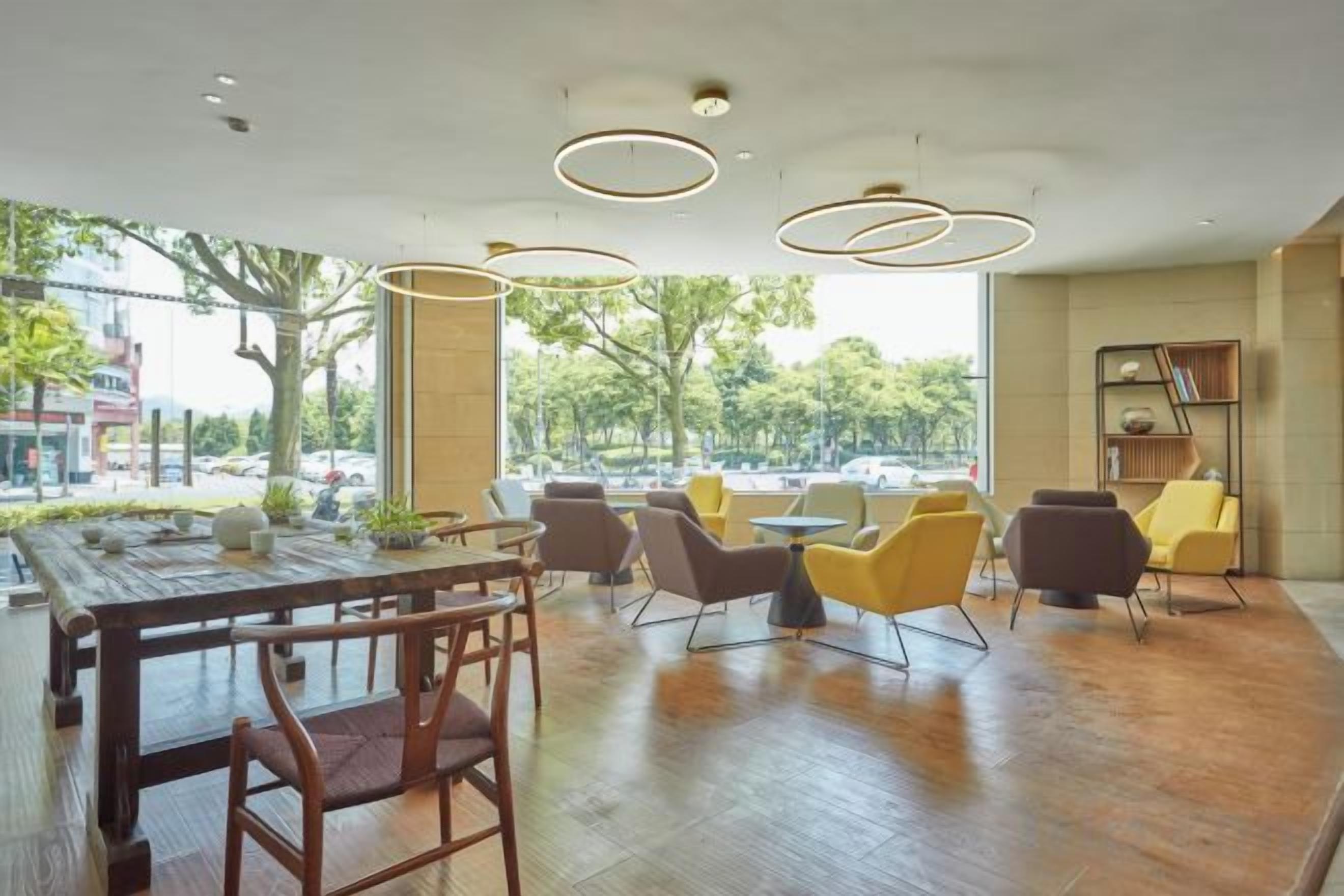 A modern interior with a wooden dining table, chairs, and a seating area with yellow and brown chairs.