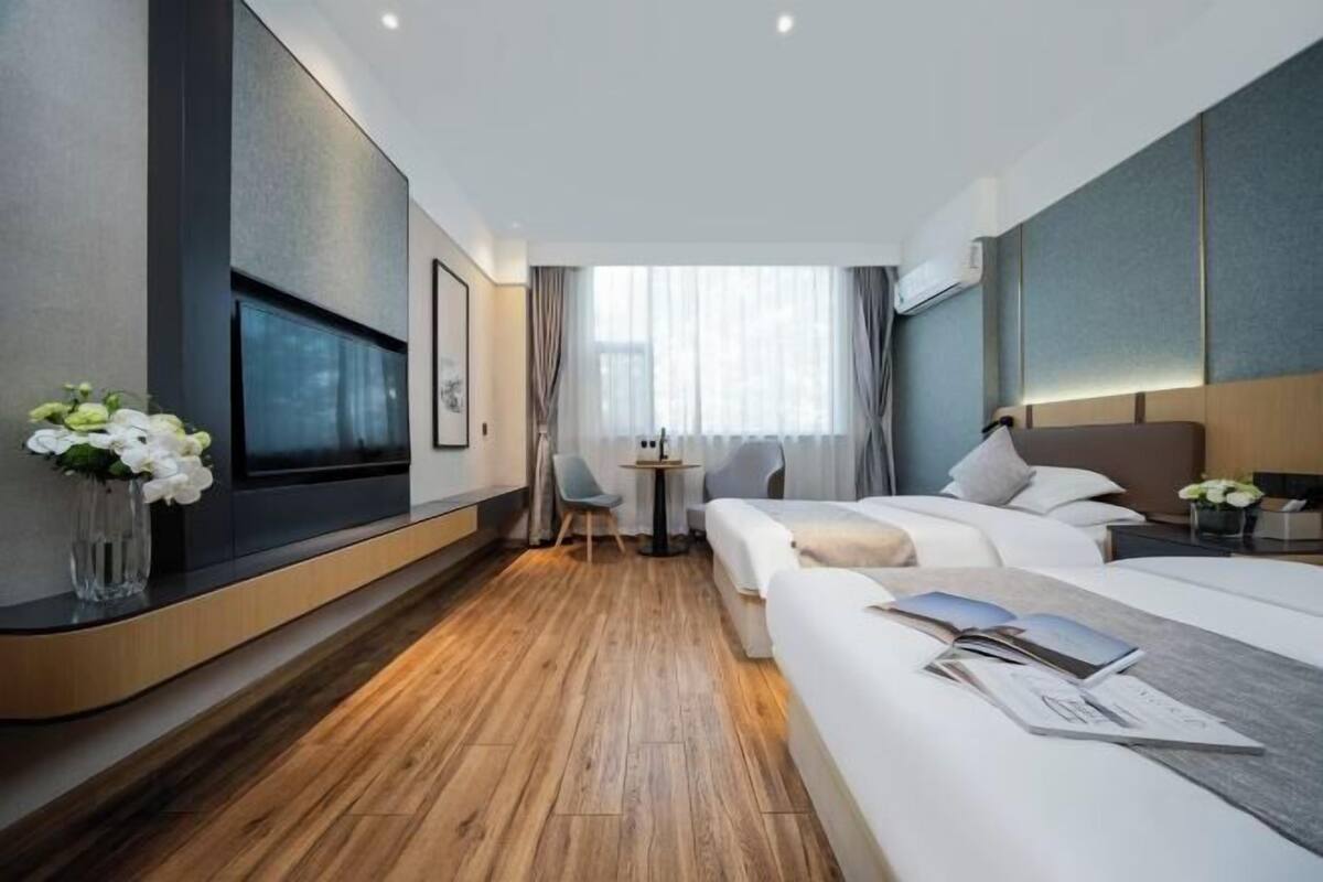 Une chambre d’hôtel moderne avec un plancher en bois, un lit, un bureau et un téléviseur fixé au mur.