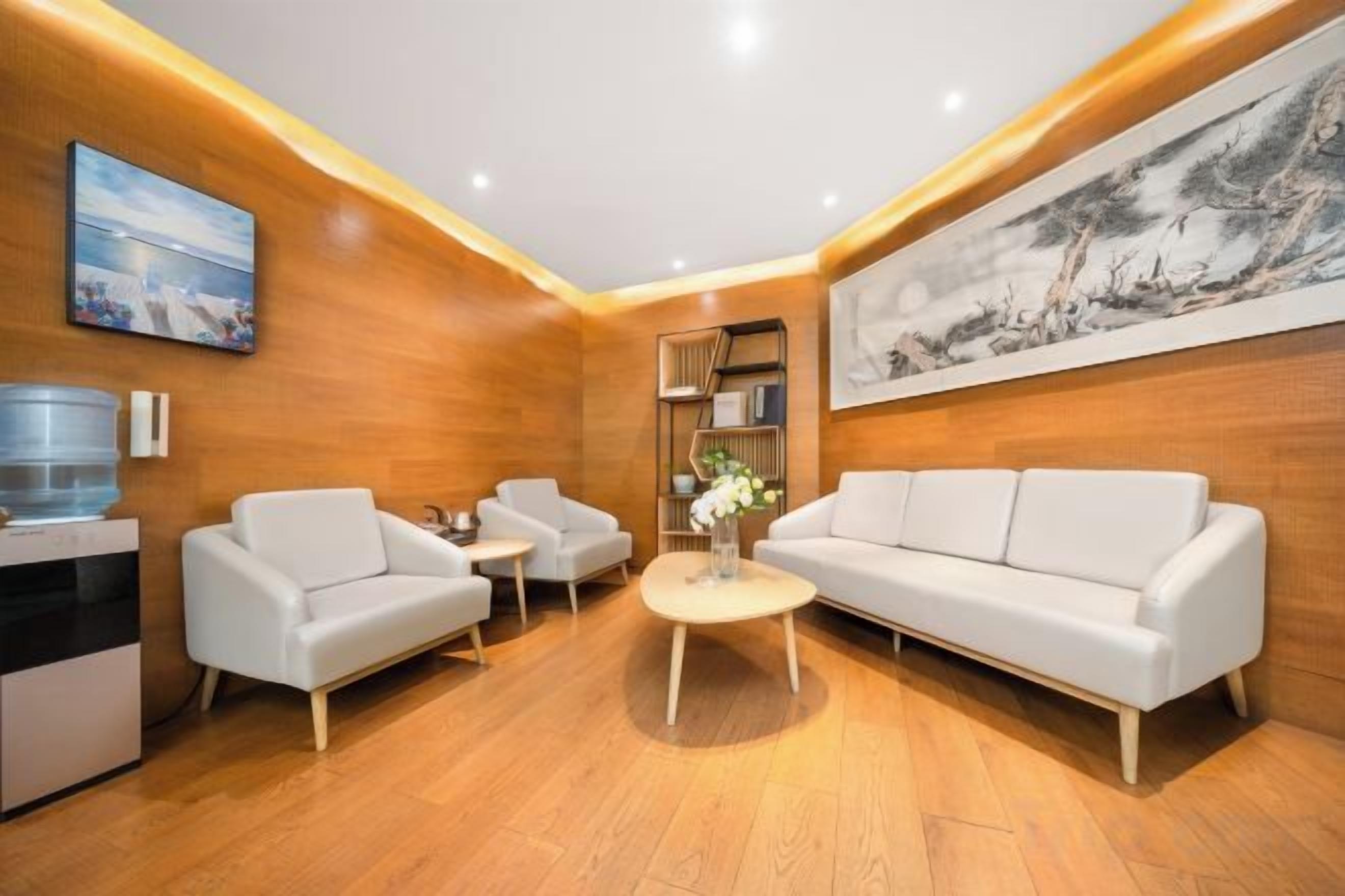 A modern living room with a sofa, two armchairs, a coffee table, and a water dispenser.