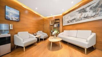 A modern living room with a sofa, two armchairs, a coffee table, and a water dispenser.
