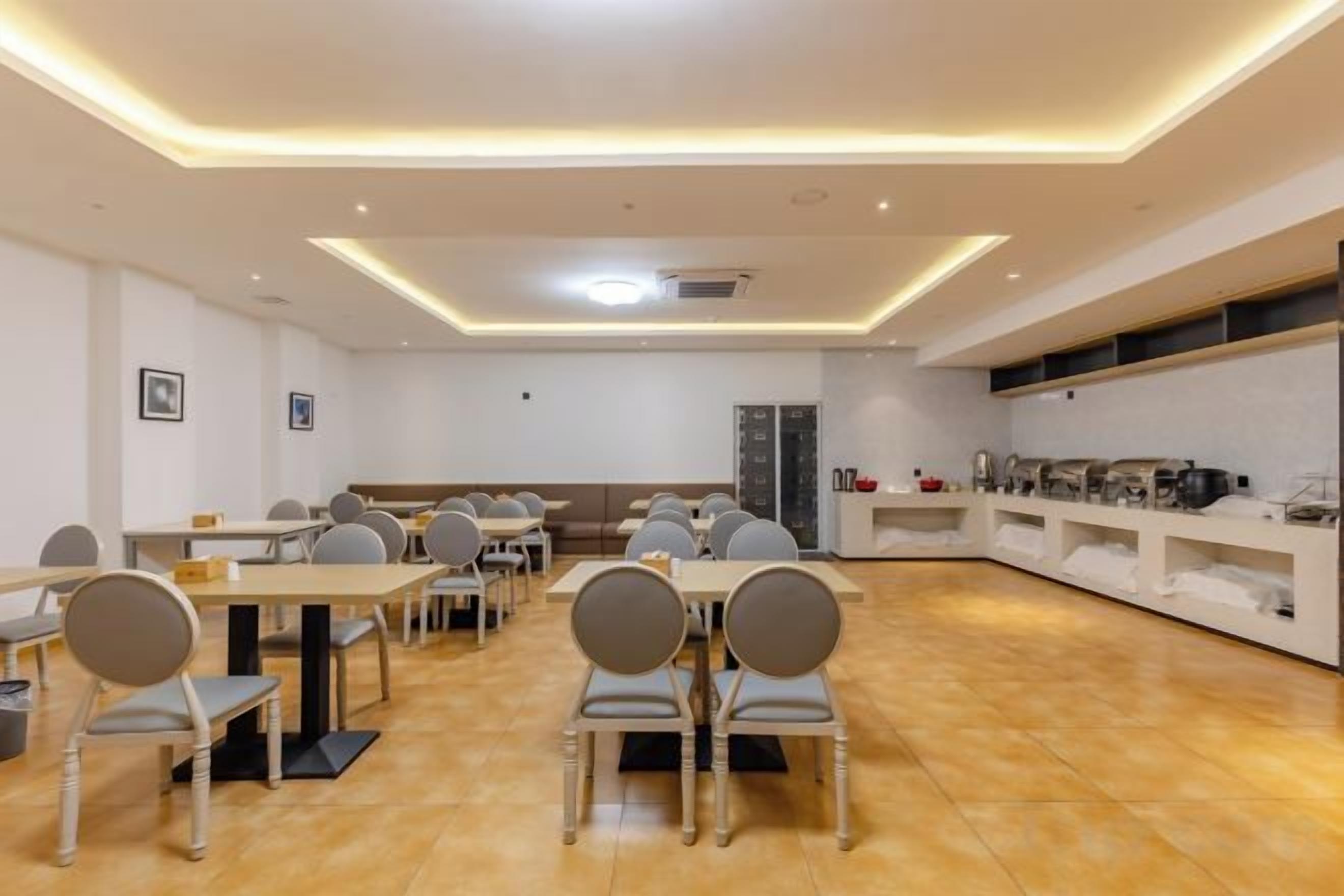 A modern dining area with tables and chairs, a kitchen area with appliances, and a seating area with a sofa.