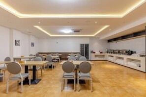 A modern dining area with tables and chairs, a kitchen area with appliances, and a seating area with a sofa. - Shiji Xinghe Hotel (Huangshan Tunxi Old Street) (Huangshan City)