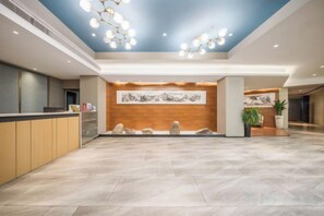 A spacious lobby with a reception desk, a wooden accent wall, and a large floor-to-ceiling artwork. - Shiji Xinghe Hotel (Huangshan Tunxi Old Street) (Huangshan City)
