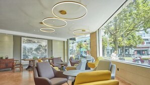 Ein modernes Interieur mit runden Deckenleuchten, bequemen Sitzmöglichkeiten und großen Fenstern mit Blick auf die Straße.