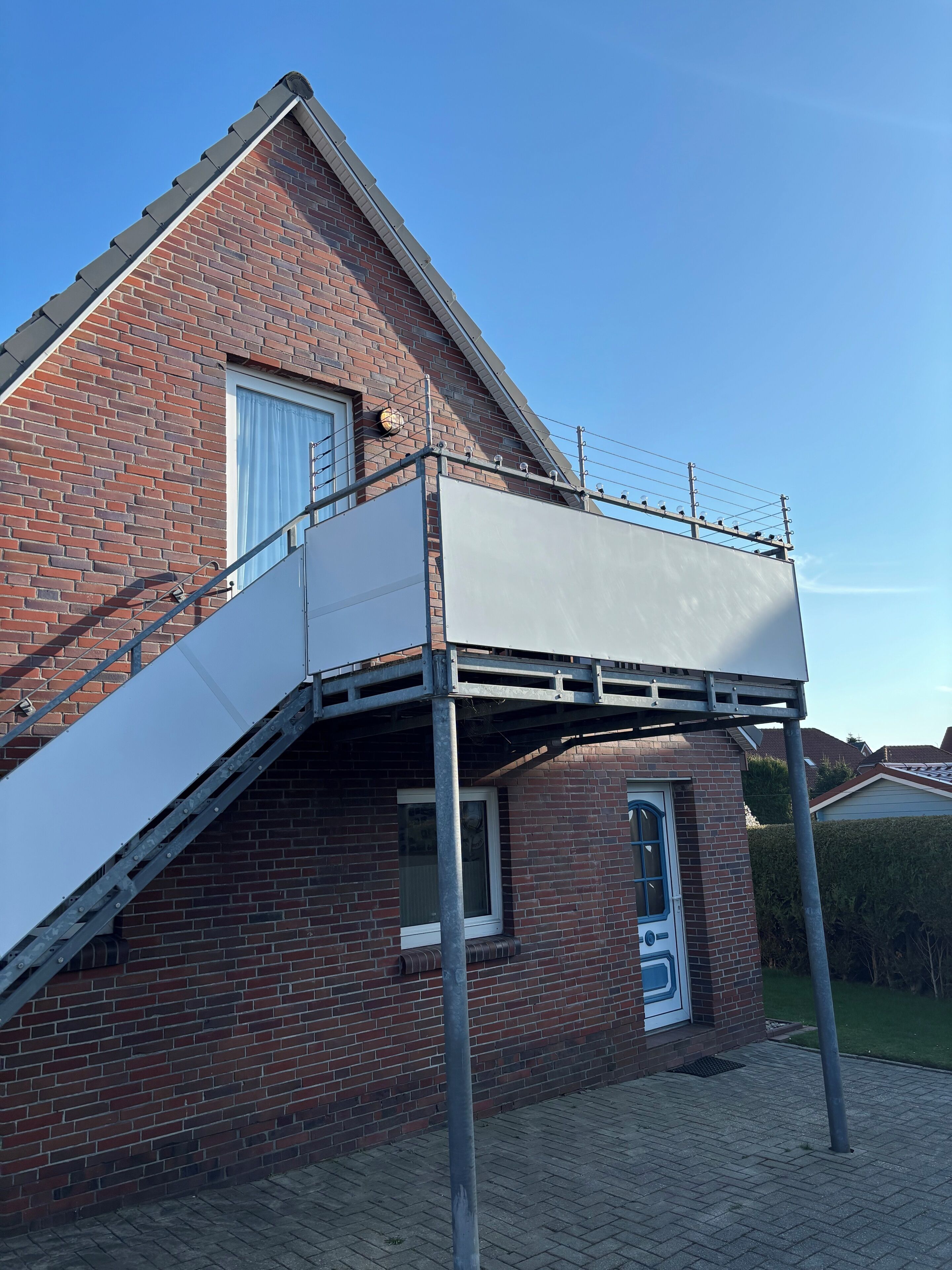 A brick house with a balcony and a door with a number.