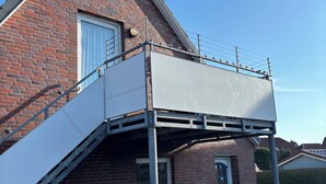 Une maison en briques avec un balcon et une porte portant un numéro.