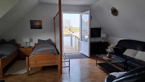 Une chambre à coucher avec un lit en bois, un canapé en cuir noir et un téléviseur fixé au mur.