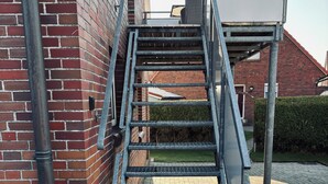 Un escalier métallique menant à un bâtiment dont la façade est en briques.