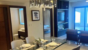 Un comedor moderno con una mesa de vidrio, cuatro sillas y una lámpara colgante contemporánea.