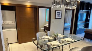 Un comedor moderno con una mesa de vidrio, sillas blancas y una lámpara de araña contemporánea.