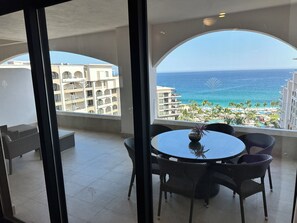 A balcony with a view of the ocean and a pool area.