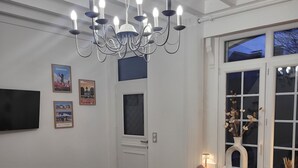 Ein Wohnzimmer mit einer Chandelieber, einem Sofa, einem Couchtisch mit Blumen und einem Fernseher an der Wand.
