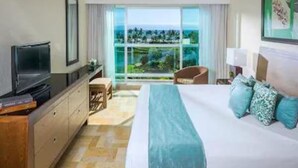 Una habitación de hotel con una cama, televisión, escritorio y vista al océano.