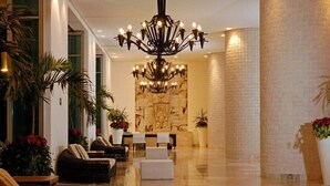 Un vestíbulo amplio con candelabro, zona de estar y mostrador de recepción.