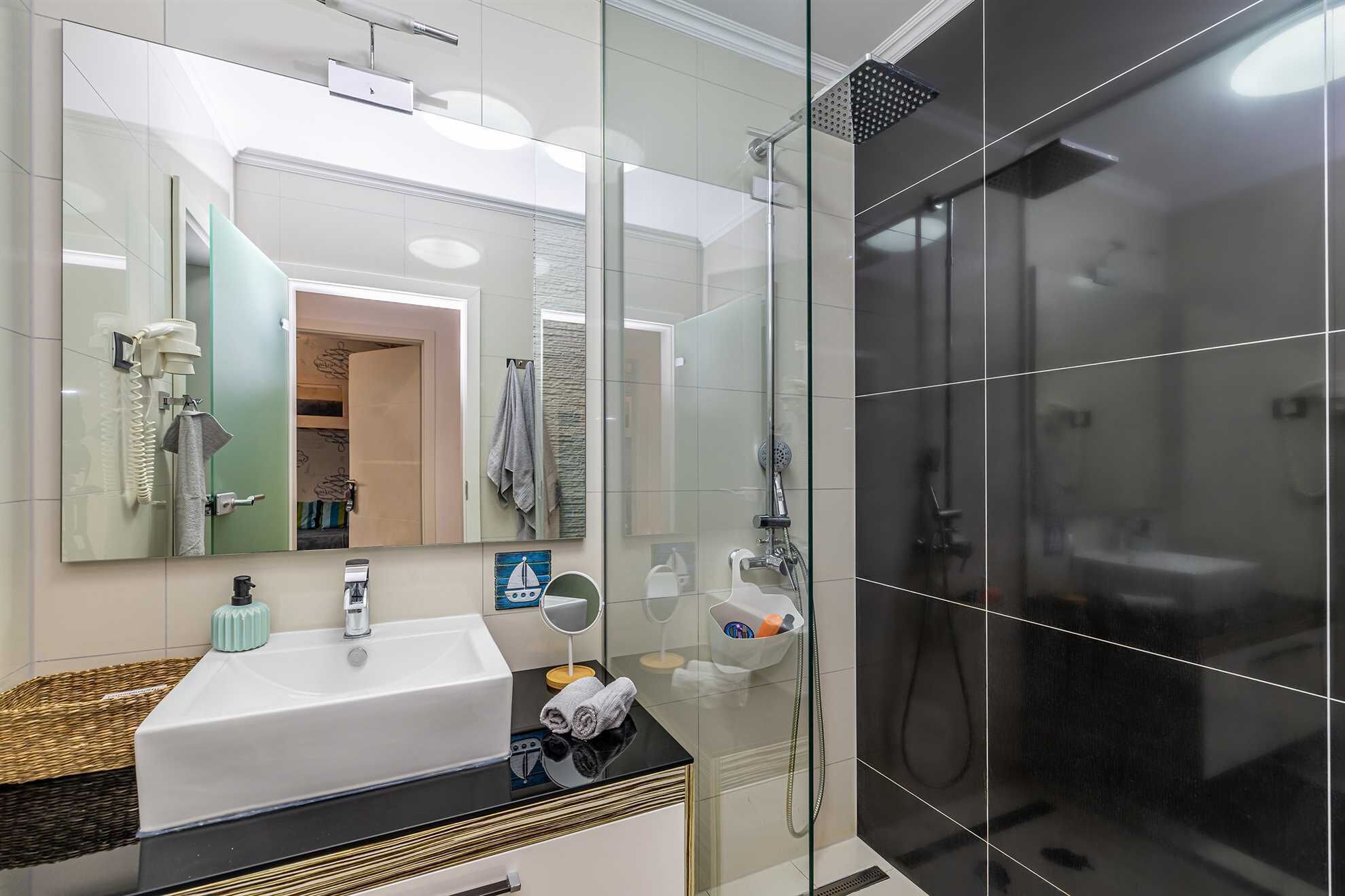 Un bagno moderno con doccia vetrata, lavabo bianco e uno specchio grande.