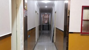 Un passadís llarg i estret amb parets blanques i un terra de rajoles, que condueix a una escala.