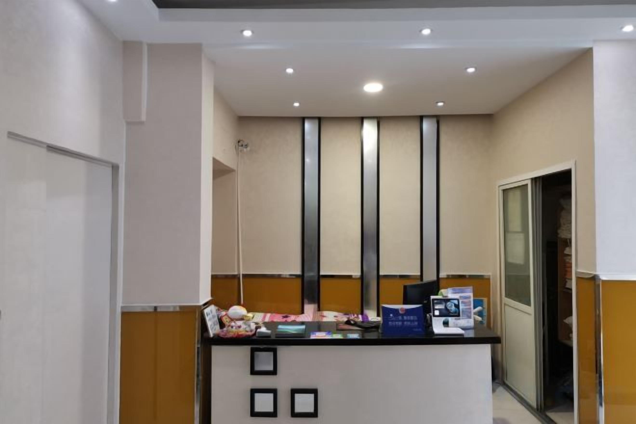 A reception desk with a counter, framed pictures, and a glass door leading to a room.