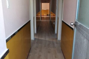 A hallway with a wooden floor, a door on the right, and a light fixture on the left. - Gulou Holiday Inn (Hangzhou)
