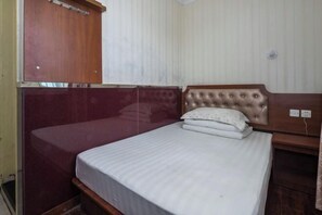 A single bed with a wooden headboard and a white mattress.