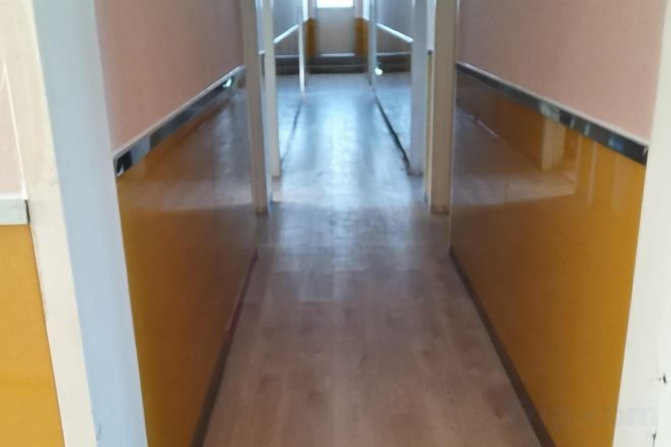 A corridor with a wooden floor and walls painted in a light color.