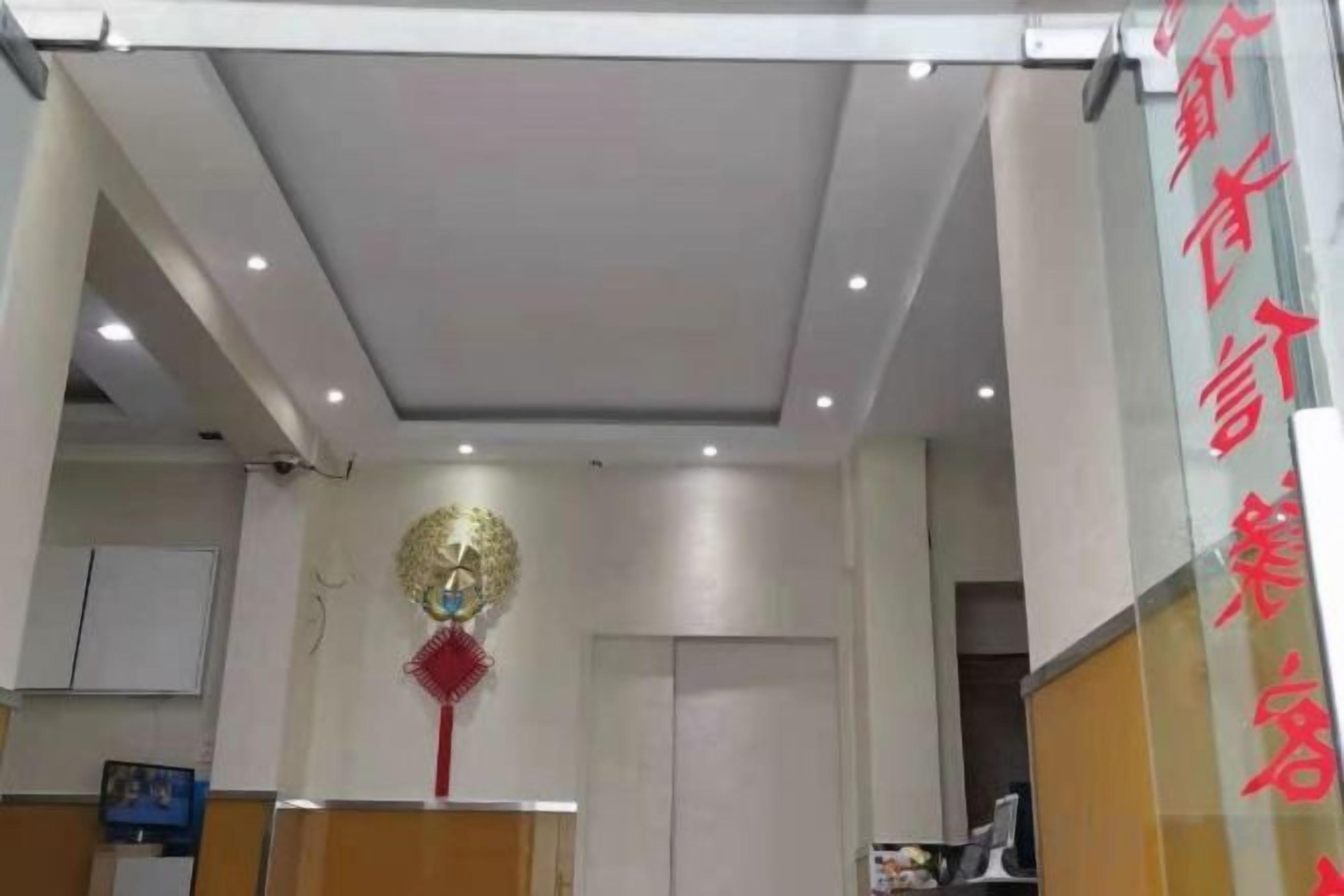 A reception area with a modern ceiling design, a decorative wall piece, and a vertical sign with red text.