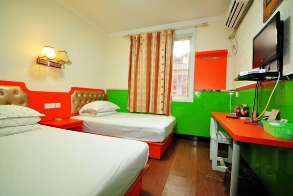 Habitación de hotel con dos camas, un escritorio, un televisor y una ventana con cortinas.
