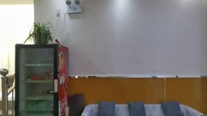 Habitació amb un sofà, un moble de vitrines i aire condicionat fixat a la paret.