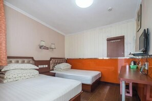 A hotel room with two beds, a desk, a television, and a window with blinds.