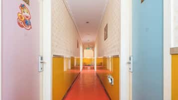 A hotel corridor with a red carpet, doors on both sides, and a sign at the end.