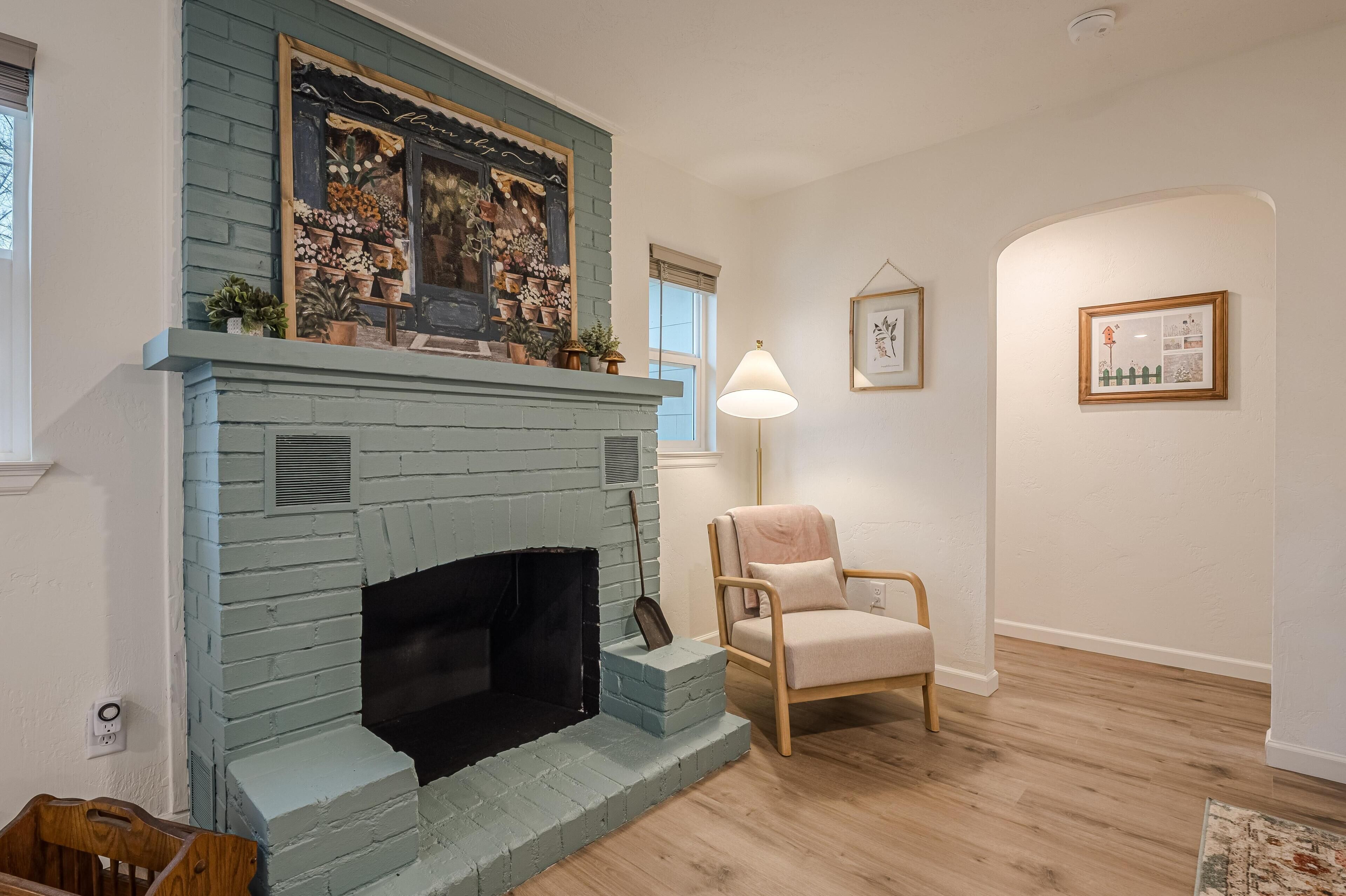 A living room with a blue brick fireplace, a wooden chair, and a lamp.