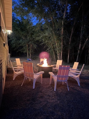 Ein Außenbereich mit Sitzgelegenheiten, einem Feuerkorb und Adirondack-Stühlen.