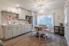 A kitchen with white cabinets, a microwave, a refrigerator, and a dining table with chairs. - Romeo & Juliet: 2 Living Areas/Kitchens! (Grand Junction)