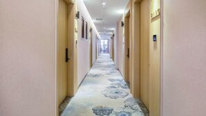 A hotel hallway with a floral carpet, wooden doors, and framed pictures on the walls. - Super 8 Plus Hotel (Beijing Tiananmen Square Qianmen Pedestrian Street) (Beijing)