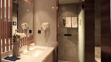 Un baño moderno con un espejo grande, un lavamanos y una zona de ducha.
