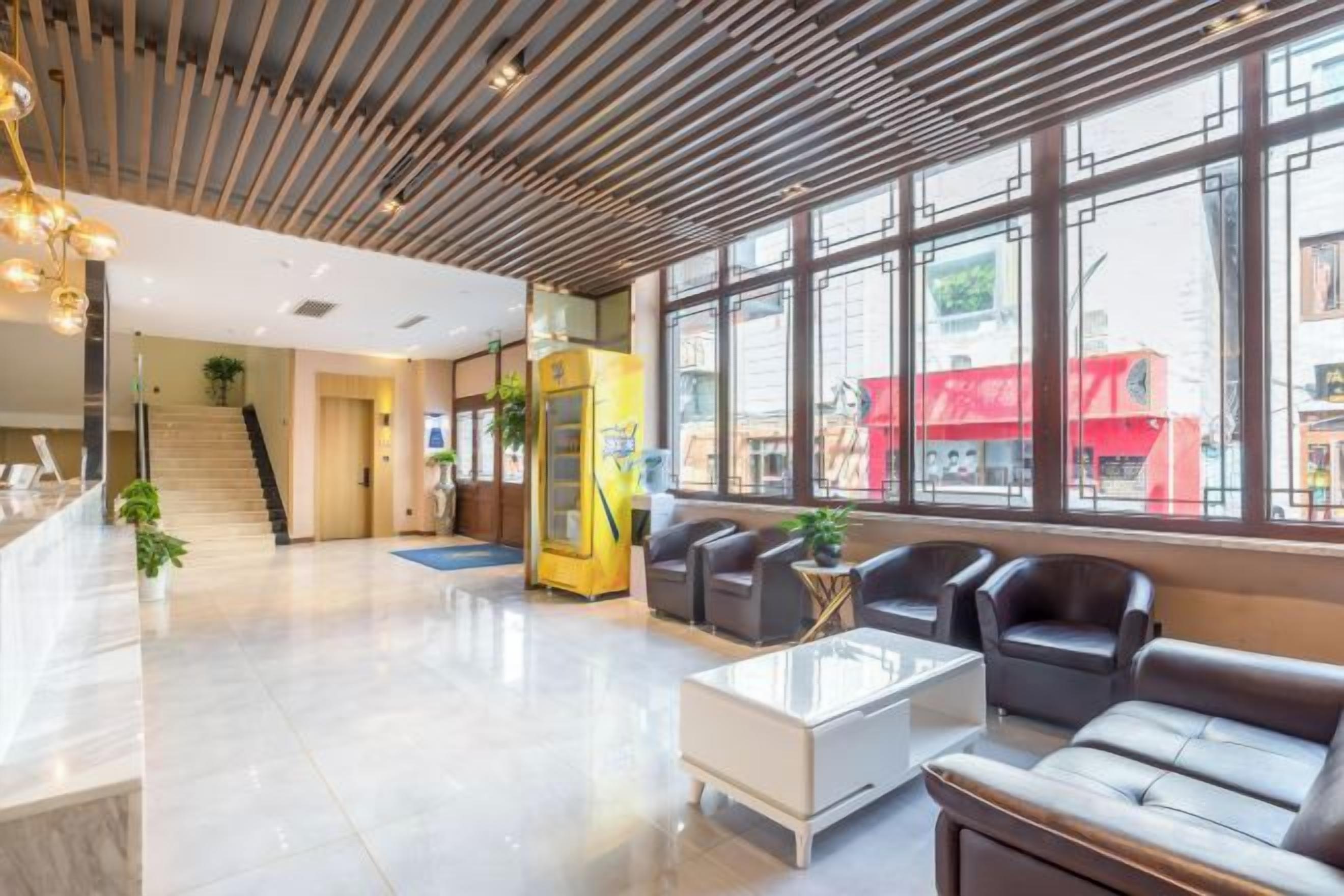 A modern lobby with a reception desk, seating area, and large windows.