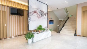A modern lobby with a large abstract painting, a staircase, and a reception desk. - Super 8 Plus Hotel (Beijing Tiananmen Square Qianmen Pedestrian Street) (Beijing)
