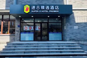 L’entrée d’un hôtel, avec une enseigne indiquant « Super 8 Hotel Premier » et un logo.