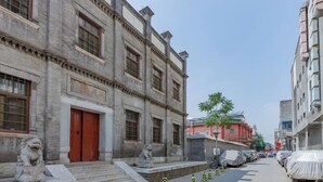 A street with traditional buildings, a red door, and a statue of a lion. - Super 8 Plus Hotel (Beijing Tiananmen Square Qianmen Pedestrian Street) (Beijing)