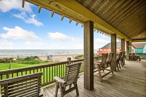 Une terrasse en bois avec des chaises donnant sur une plage.
