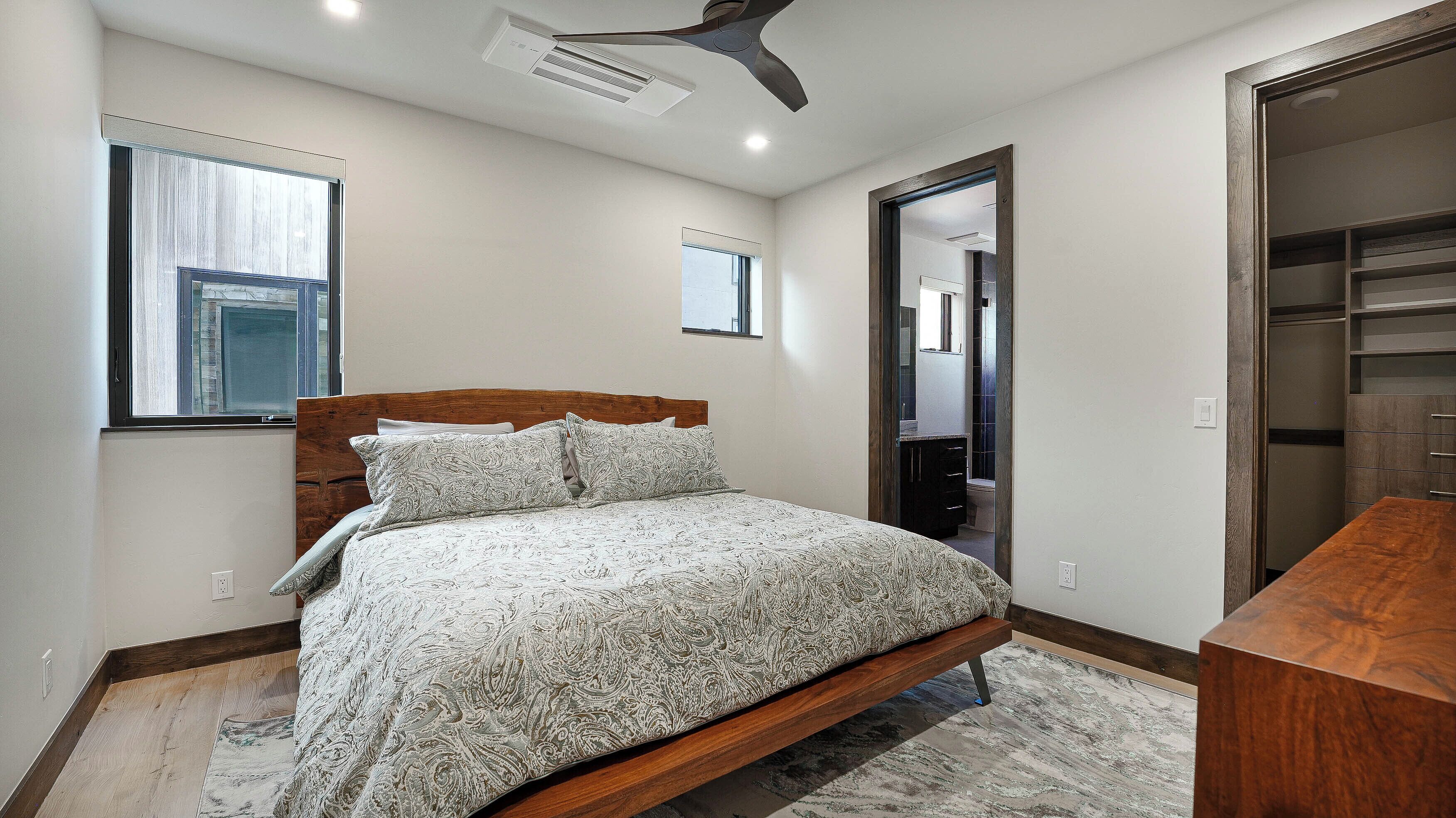 A bedroom with a wooden bed, a window, a ceiling fan, and a walk-in closet.