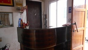 A reception desk with a wooden finish, a door with a handle, and a window with blinds.
