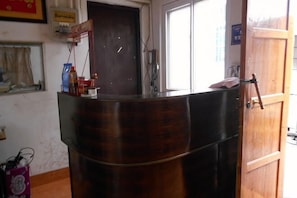 Un mostrador de recepción con detalles de madera, una puerta con manija y un ventanal con persianas.