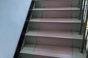 Um conjunto de degraus com corrimão e parede revestida de azulejos.
