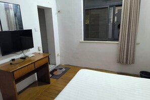 A hotel room with a wooden desk, a flat-screen TV, a bed, and a window with curtains. - Guangde Linyuan Hotel (Guangde)