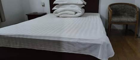 A neatly made bed with a dark headboard and a stack of pillows.