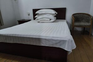 A neatly made bed with a dark headboard and a stack of pillows. - Guangde Linyuan Hotel (Guangde)