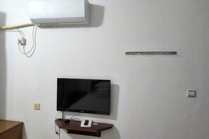 A room with a mounted TV, a white air conditioner, and a power strip on the wall. - Guangde Linyuan Hotel (Guangde)