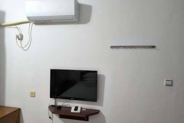 A room with a mounted TV, a white air conditioner, and a power strip on the wall. - Guangde Linyuan Hotel (Guangde)